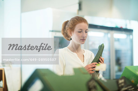 Woman in shop holding cucumber