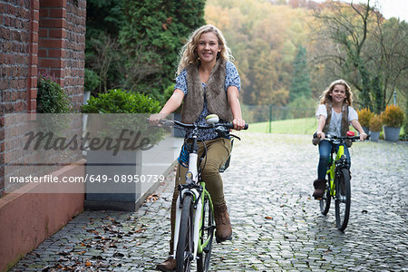 Two sisters cycling together in park