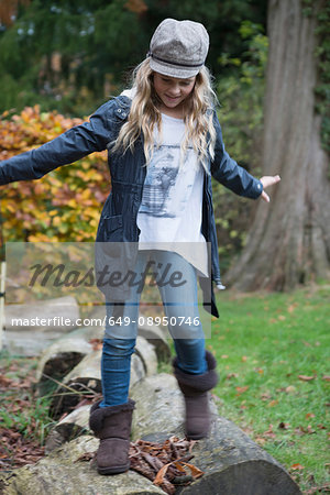 Girl stepping over logs in park