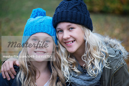 Portrait of blond haired sisters wearing knit hats in garden