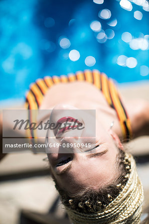 Young woman with dreadlocks, beside swimming pool, elevated view