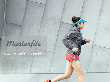 Mature female ultra runner running in city