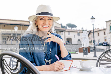 Portrait of mature woman writing in notebook at sidewalk cafe, Fiesole, Tuscany, Italy