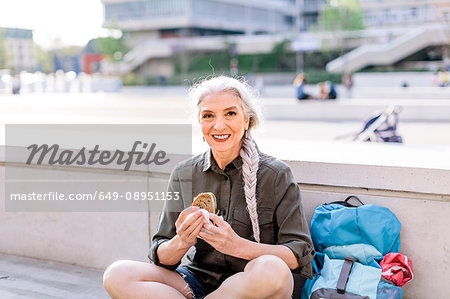 Portrait of mature female backpacker with sandwich in bus station, Scandicci, Tuscany, Italy