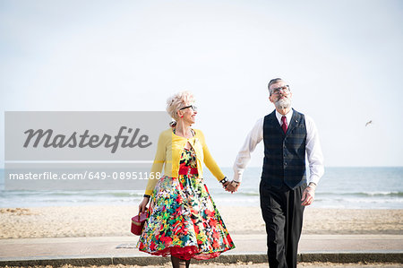 1950's vintage style couple holding hands and strolling on beach