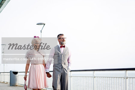 1950's vintage style couple strolling hand in hand on pier