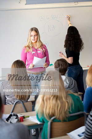 Girl standing and reading in front of class