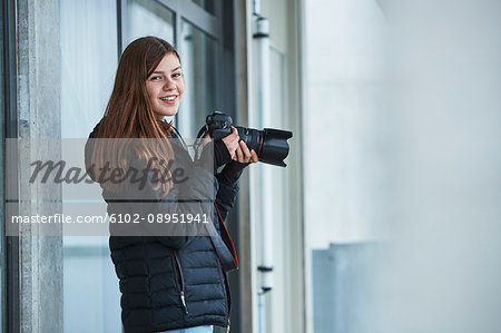 Smiling teenage girl holding digital camera