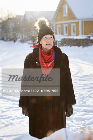 Senior woman standing in front of house in winter