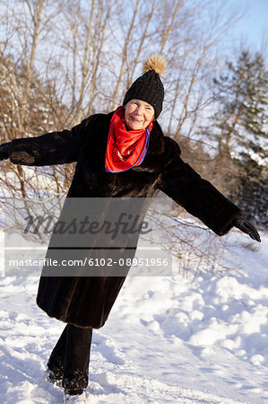 Senior woman walking in forest in winter