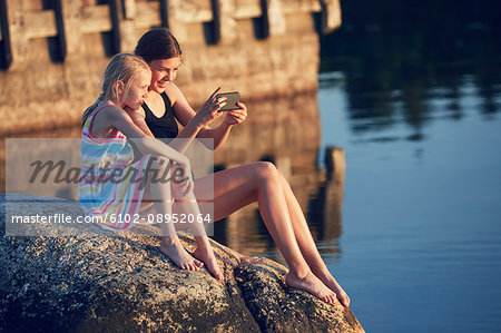 Girls using cell phone by lake