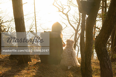 Woman and dog sitting at water