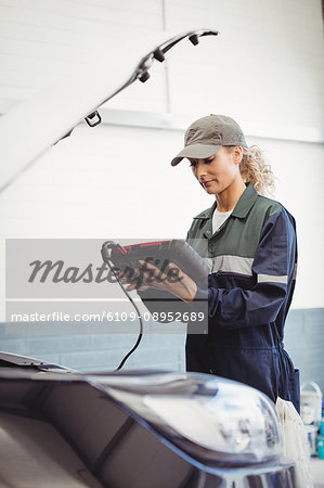 Female mechanic using electronic diagnostic device Female mechanic using electronic diagnostic device