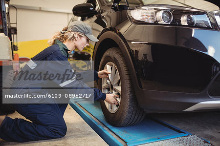 Female mechanic examining a car wheel