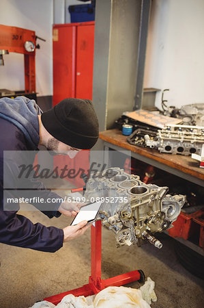 Mechanic using digital tablet on car parts