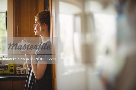 Thoughtful woman having coffee in kitchen