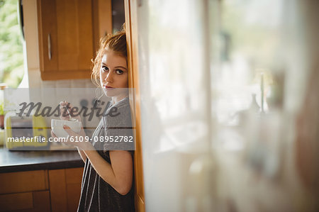 Portrait of woman having coffee in kitchen at home