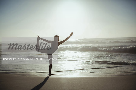 Woman performing yoga on beach