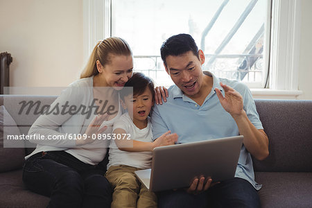 Family having video chat on laptop in living room