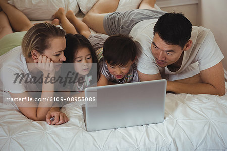 Happy family using laptop in bedroom