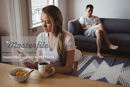 Woman using digital tablet while having breakfast