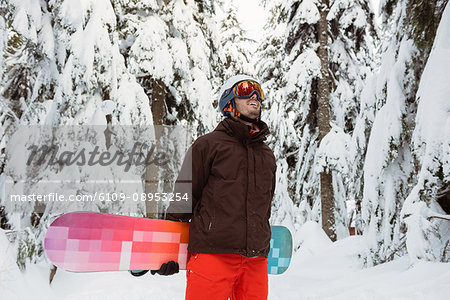 Man standing and holding a snowboard