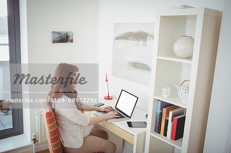 Pregnant woman using laptop in study room