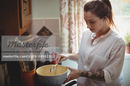Woman standing and preparing meal in kitchen