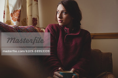 Thoughtful woman sitting and holding a coffee cup