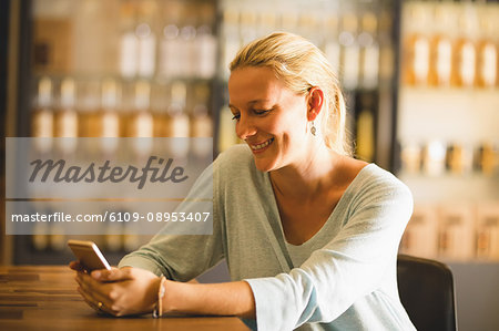 Smiling saleswoman using mobile phone at table in supermarket