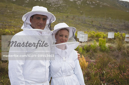 Portrait of confident male and female beekeepers at apiary