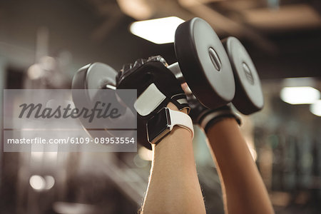 Hands of fit woman exercising with dumbbells in the gym