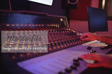 Hands of male audio engineer using sound mixer in recording studio