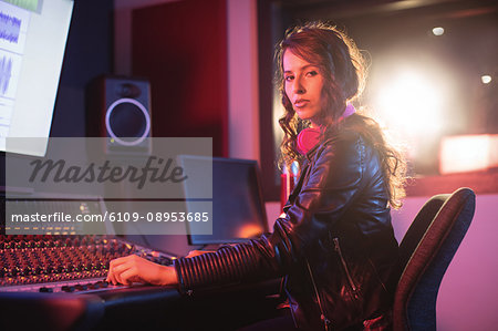 Portrait of female audio engineer using sound mixer in recording studio