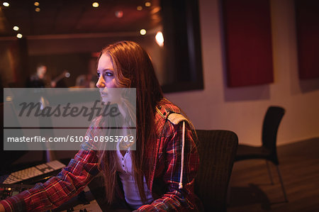 Female audio engineer using sound mixer in recording studio