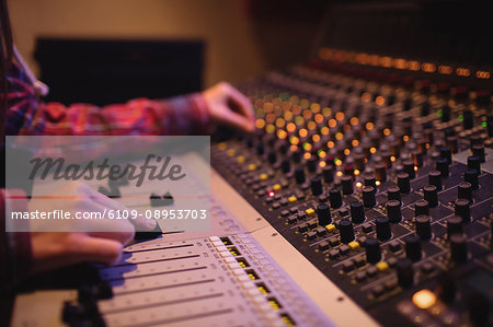 Hands of female audio engineer using sound mixer in recording studio