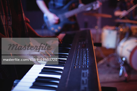 Mid section of musician playing electronic piano in recording studio