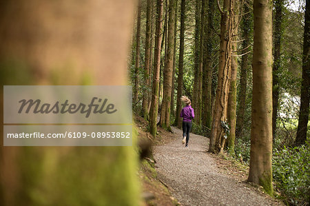 Rear view of woman jogging in forest