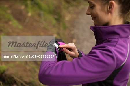 Beautiful woman using smart watch in the forest