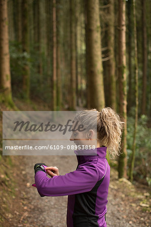 Beautiful woman using smart watch in the forest