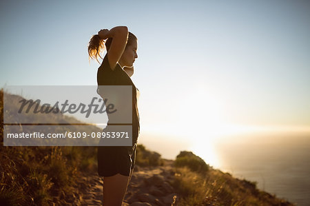 Young female hiker holding her hairs at countryside