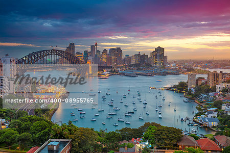 Cityscape image of Sydney, Australia with Harbour Bridge and Sydney skyline during sunset.