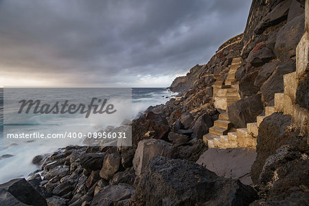 Sunset and coastline with high cliffs and long exposure of waves breaking over volcanic rocks in Terceira island, Portugal