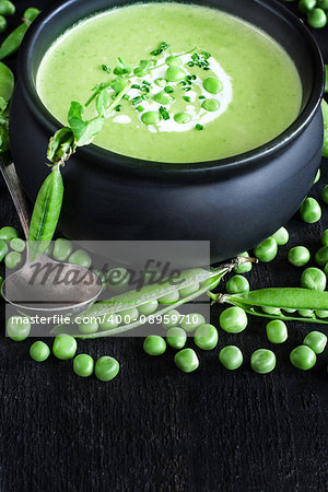 Green peas soup on dark wooden background. Low key photo. Copy space background.