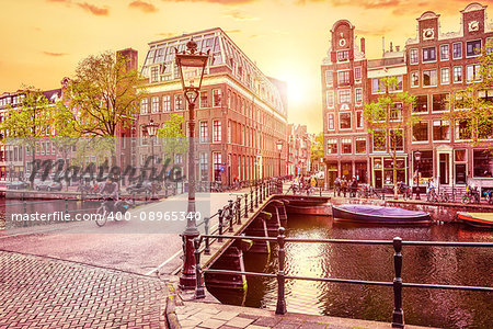 Channel in Amsterdam Netherlands Holland houses under river Amstel. Landmark old european city spring landscape with sunshine.