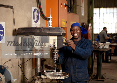 Factory worker operating drill press in magnet factory, Gauteng, South Africa