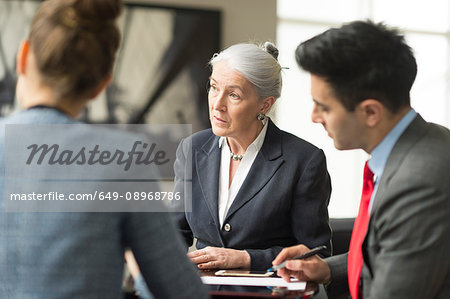 Businessman discussing with female colleagues in boardroom meeting