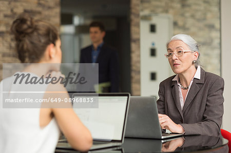 Mature businesswoman and female colleague having discussion over office desk