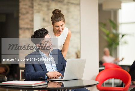 Businessman and woman looking at laptop in office