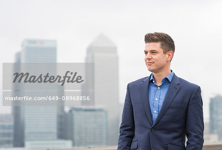 Confident  businessman gazing from city office roof terrace, London, UK